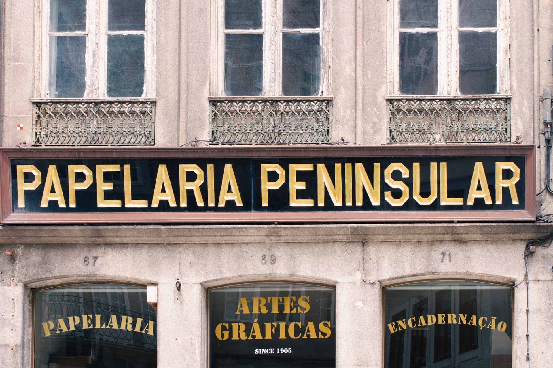 A stationery and arts materials shop in Porto, Portugal, with a beautiful shop sign in old style typography.