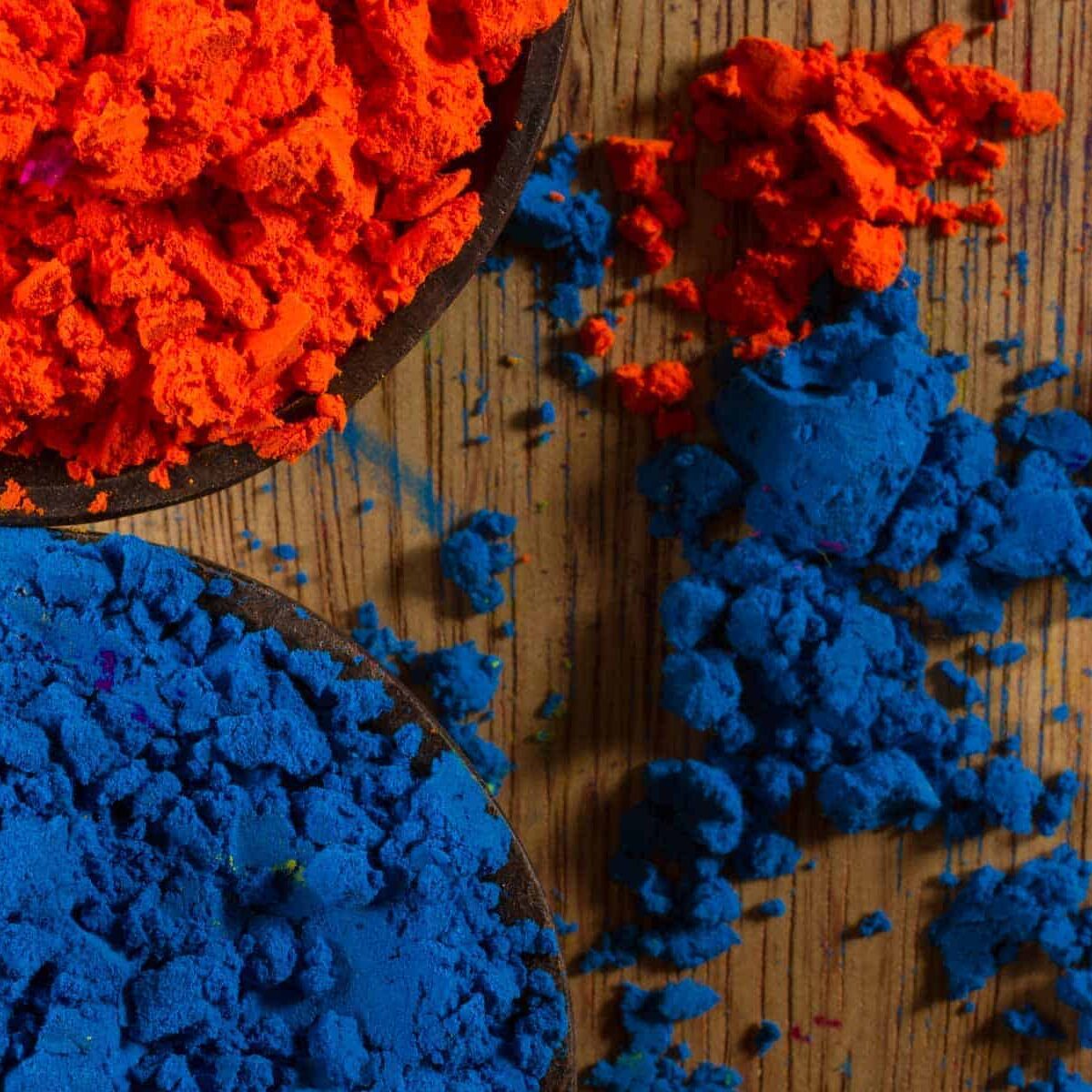 Colour harmony – complementary colours: blue and orange pigments in two small wooden bowls, spilling over onto a rustic wooden table. Photo by Piccia Neri.