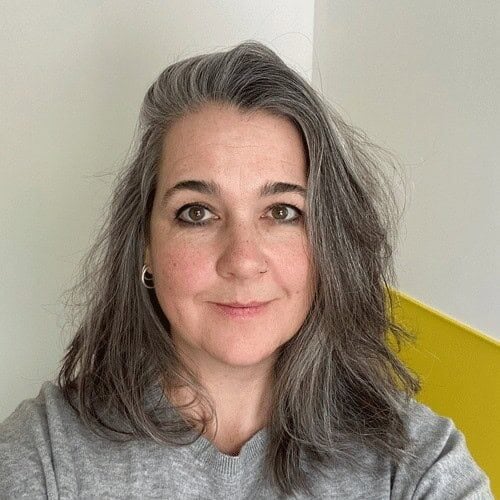 Portrait of Deb Murray, a white woman in her 50s with long hair, looking directly at the camera